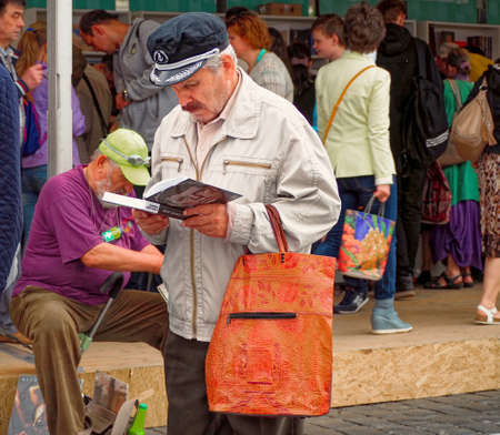 Moscow, Russia - June 5, 2016: Standing middle aged man reading a book at a book fair tent on the Moscow Book Festivalのeditorial素材