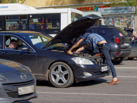 Voronezh, Russia - May 1, 2018: A man opening the hood of a stopped car eliminates the problem directly on the roadway of a city streetのeditorial素材