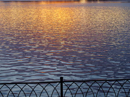 Sunrise over the lighthouse in the sea and patch of sunlight on the water surfaceの写真素材