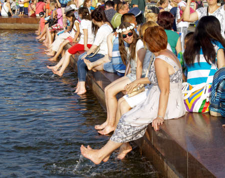 Moscow, Russia, July 30, 2016: Communicating among themselves women sitting on the parapet of the fountain and dangling bare feet in the waterのeditorial素材