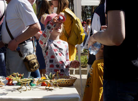 Voronezh, Russia - May 1, 2018: A girlie holds in hands and examines a toy from a street table with curly toysのeditorial素材