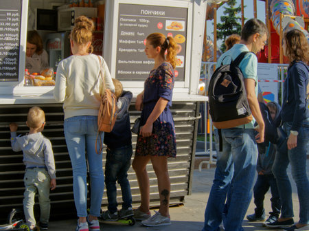 Moscow, Russia - May 26, 2018: Parents with children at the kiosk fast food with pastries on the street near the playgroundのeditorial素材