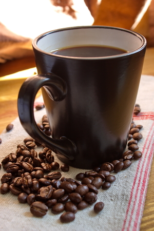 cup of coffee with beans on flax tableclothの写真素材