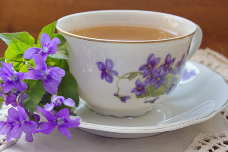 Old china tea cup with a bouquet of violetsの写真素材