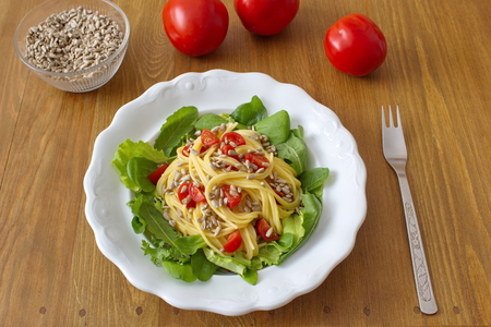 Consists healthy dinner of salad and pasta with tomatoes and sunflower seedsの写真素材