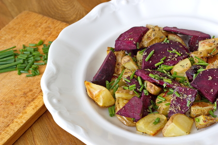 pieces of beetroot served with baked potatoes and chive on the wooden tableの写真素材