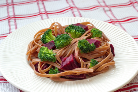 spaghetti served with beetroot and broccoli on checkered tableclothの写真素材