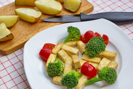 pieces of roasted tofu served with fresh vegetable and potatoesの写真素材