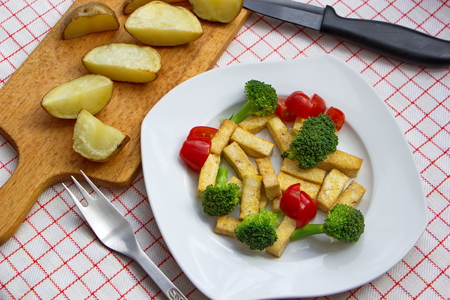 pieces of tofu served with broccoli, tomatoes and baked potatoesの写真素材
