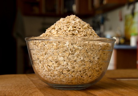 Oat groats in a glass bowl on a wooden table