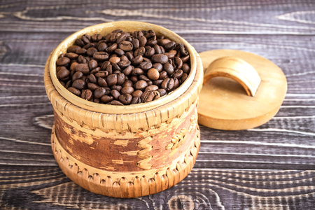 Roasted coffee beans in wooden basket on a wooden backgroundの写真素材