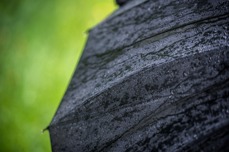 Big black umbrella in rain drops against a background of green grass. Close-upの写真素材