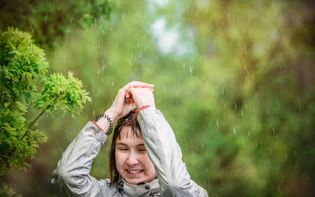 young girl covers her head with her hands from the rainの写真素材