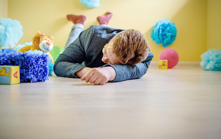 young male father fell asleep on the floor in a children's room among toysの写真素材