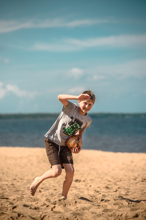 Happy boy on a sunny day at the beach playing with a ballの写真素材