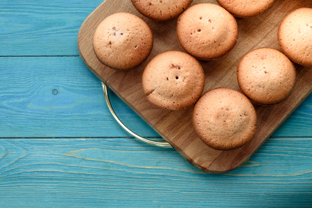 Fresh muffins on a cutting board on a wooden blue background. Background.Texture of freshly baked...