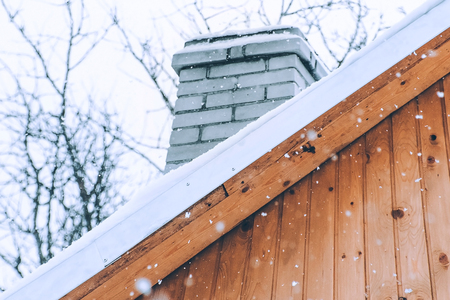 Snowfall over a wooden roof. Winter day.の写真素材