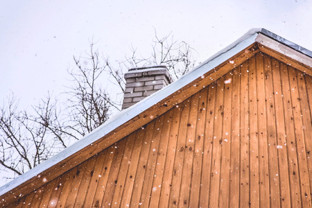 Snowfall over a wooden roof. Winter day.の写真素材