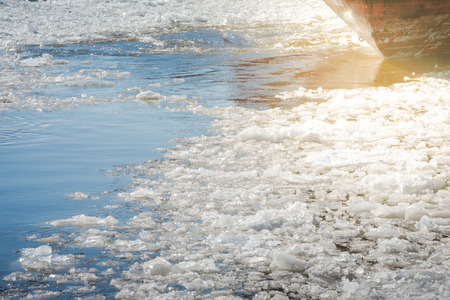 stern of ship sailing along a river covered with ice floes in early spring.の写真素材