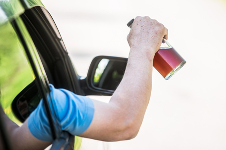 Alcohol, bottle,  car and concept of drunk driving - the person holds in hand a bottle with alcoholic drink, driving the car.の写真素材