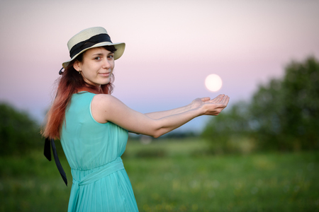 Beautiful girl in the field against the sky with the moon-lifestyle conceptsの写真素材