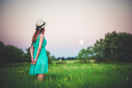 Beautiful girl in the field against the sky with the moon-lifestyle conceptsの写真素材