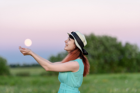 Beautiful girl in the field against the sky with the moon-lifestyle conceptsの写真素材