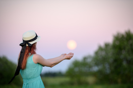 Beautiful girl in the field against the sky with the moon-lifestyle conceptsの写真素材