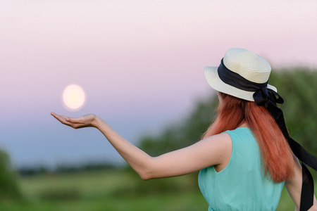 Beautiful girl in the field against the sky with the moon-lifestyle conceptsの写真素材