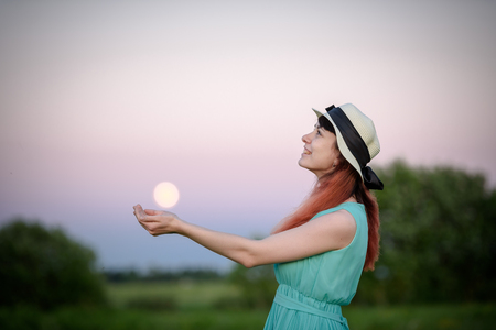 Beautiful girl in the field against the sky with the moon-lifestyle conceptsの写真素材