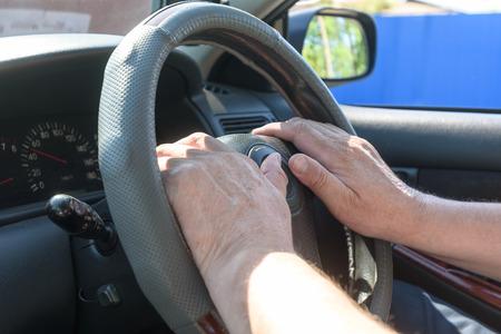 men's hands on the steering wheel of the car, inside
