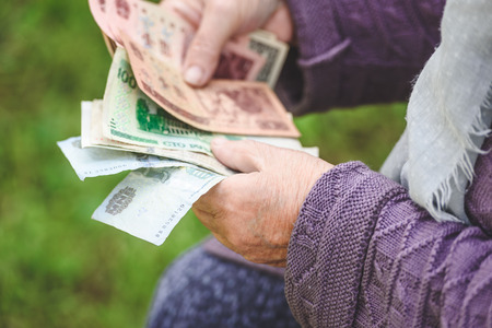 The old woman considers banknotes - hands and money close upの写真素材