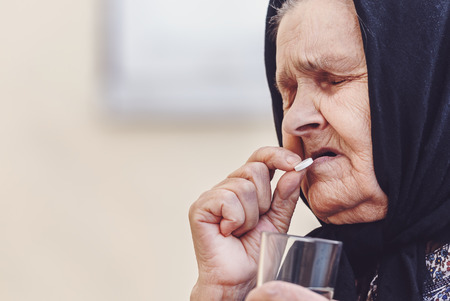 Grandmother, pill, health and the concept of a healthy lifestyle - an old woman takes pills, close-up, tonedの写真素材