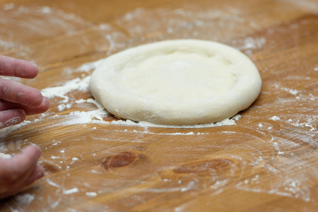 Pizza dough. Basis for baking pizza on a wooden table, close-upの写真素材