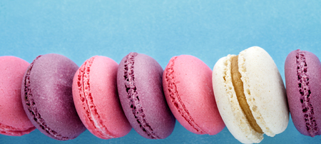 Row of colorful french macarons on blue background. Top view.の写真素材