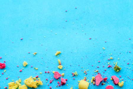Blue background with multicolored cake crumbs, top viewの写真素材