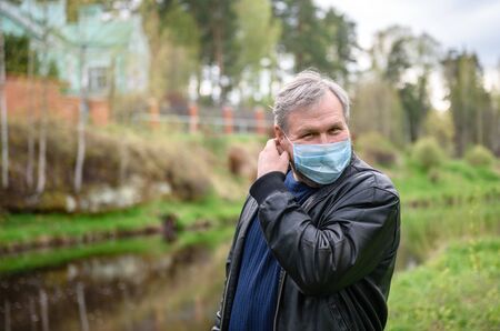 Happy man on a nature walk by the river. The man removes the medical mask from his face.の写真素材