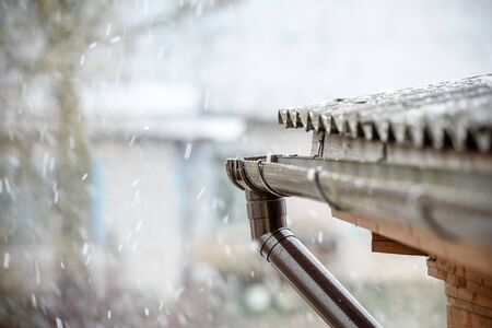 Snow falls on the roof of the house-the concept of bad weather in the springの写真素材