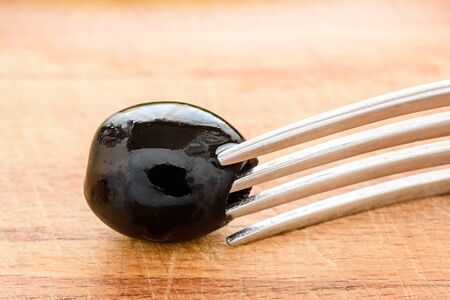 One Berry black olives on fork, close-upの写真素材