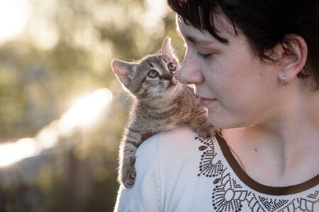 A small kitten sitting on the shoulder of a girl on a walk.の写真素材