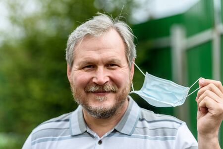 The man joyfully removes the medical mask from his face. End of the viral pandemic quarantine.の写真素材