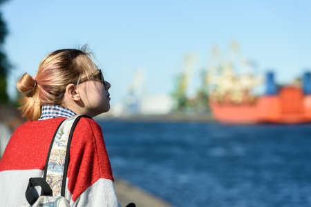 A girl alone in a commercial seaport on a walk. Russia, Saint Petersburg, may 30, 2020