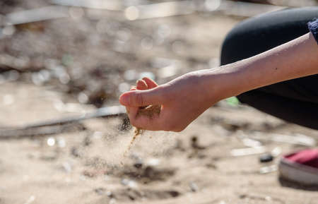 Hand is pouring coral sand on a beachのeditorial素材