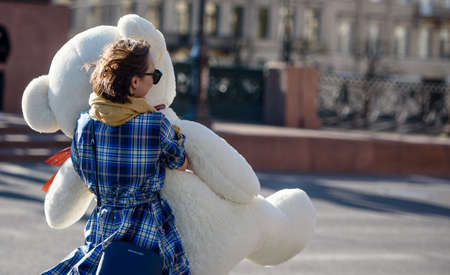 Russia, Saint Petersburg, may 30, 2020: a Happy girl on the streets of the city carries a huge Teddy bear toyのeditorial素材
