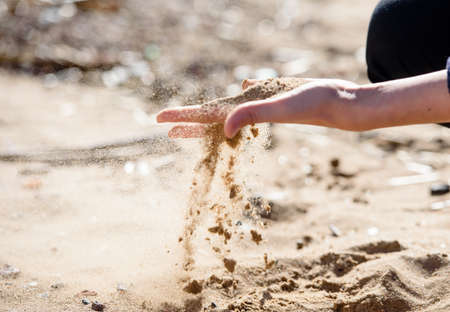 Hand is pouring coral sand on a beachのeditorial素材