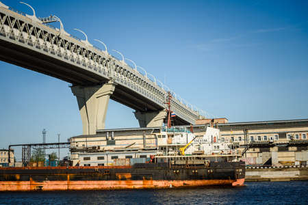 Russia, Saint Petersburg, may 30, 2020:Main road bridge over the seaport. Ships and cranes.のeditorial素材