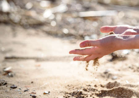 Hand is pouring coral sand on a beachのeditorial素材