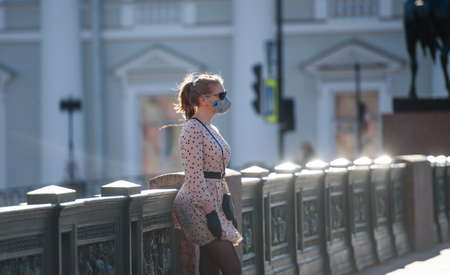 Russia, Saint Petersburg, may 30, 2020: a girl in a medical mask on the city bridge on a walkのeditorial素材