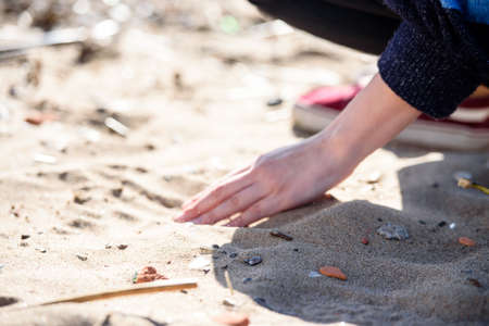 Hand is pouring coral sand on a beachのeditorial素材