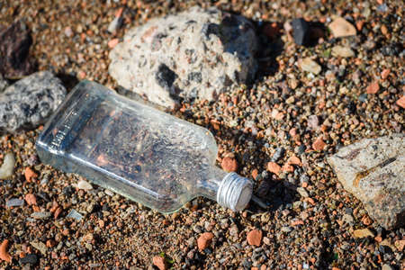 An empty liquor bottle on a sandy beach. Saint Petersburg, Russia, may 30, 2020のeditorial素材